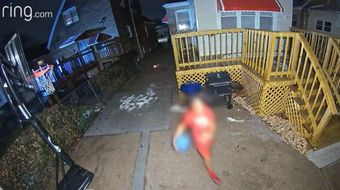 A child, face blurred out, in red T shirt with blue ball in the backyard of a Gresham home.